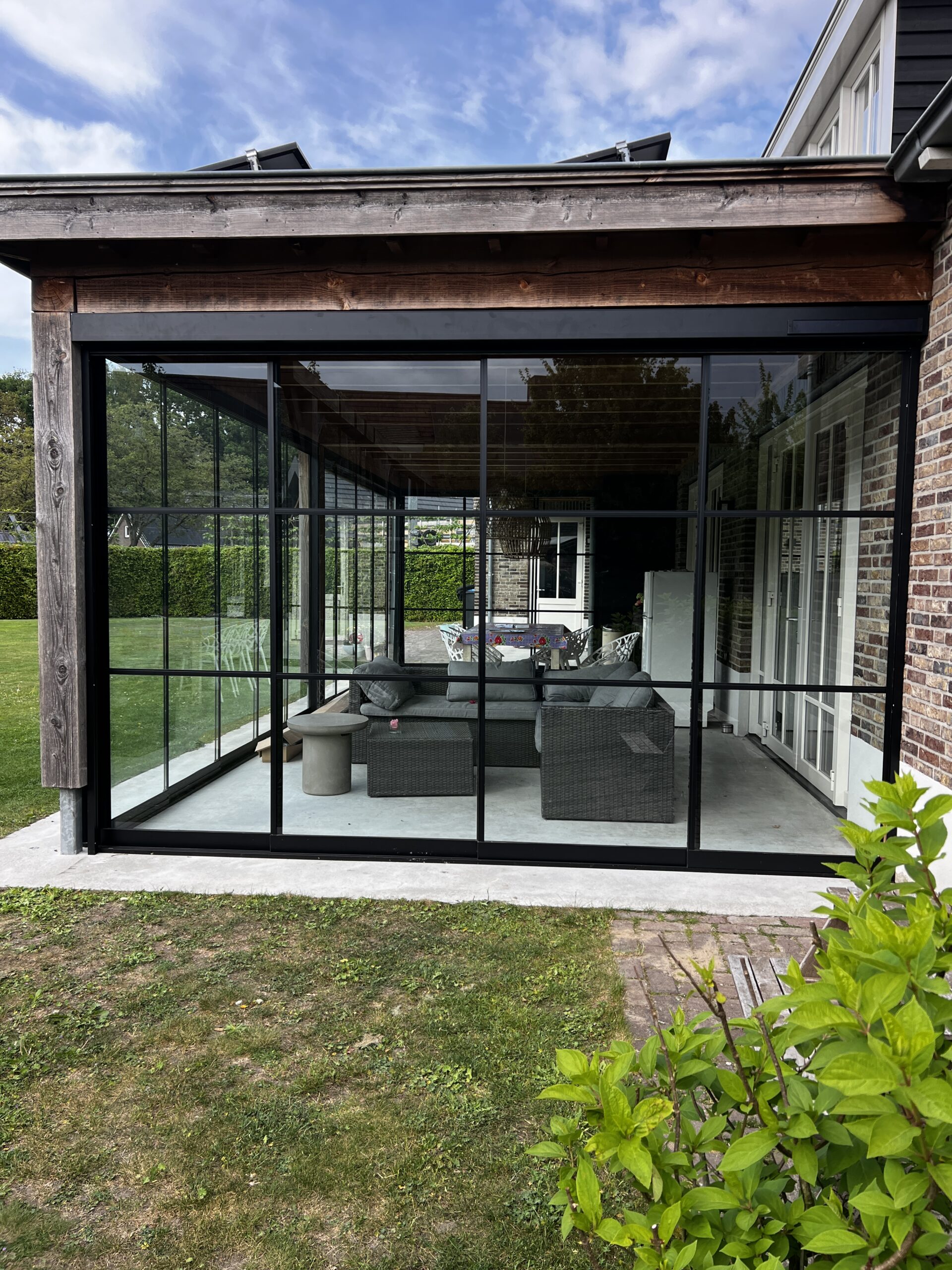Aluminium veranda met glazen dak aan woning geplaatst door AluSolutions