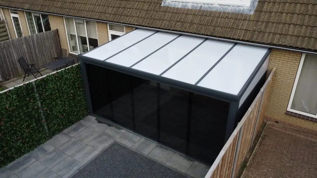 Polycarbonaat veranda in een moderne achtertuin met tuinmeubelen geplaatst door Alu Solution