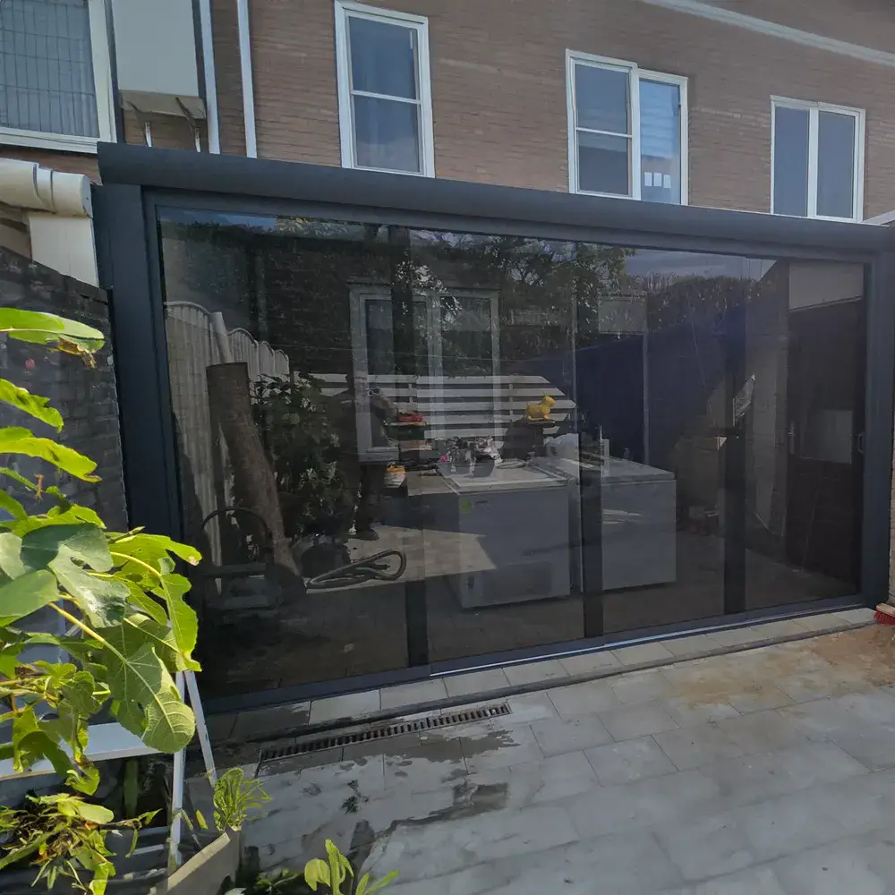 Gezin geniet van een middag onder een aluminium veranda met glazen dak geplaatst door Alu Solution