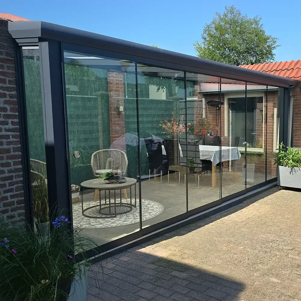 Moderne veranda met glazen dak en tuinmeubilair geplaatst door Alu Solution